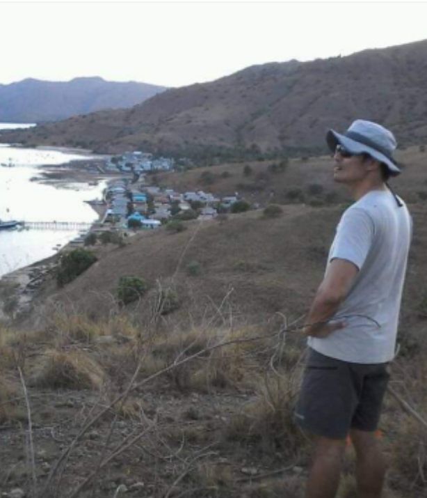 Salah seorang wisatawan mengunjungi desa Komodo di Pulau Komodo. Ia berdiri di atas bukit dan menyaksikan pemandangan desa Komodo dan lautan lepas di Taman Nasional Komodo.